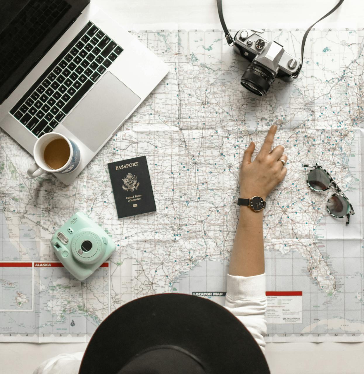 Overhead flatlay: map, notebook, passport, analogue camera and morning coffee